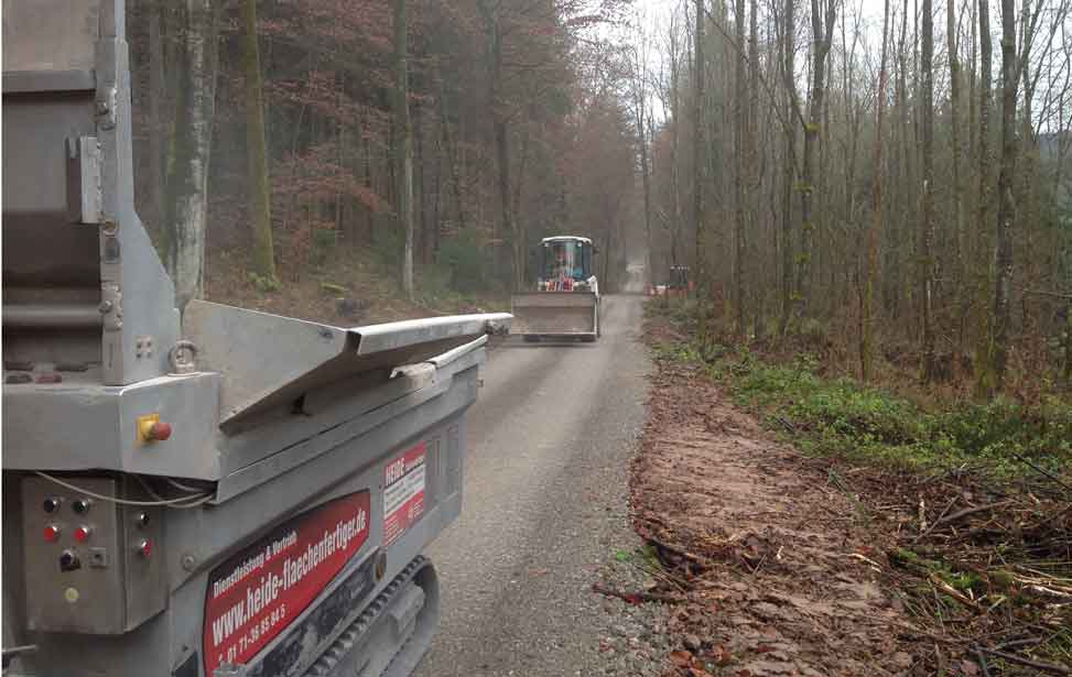 Einbau einer Tragschicht und Herstellung des Unterbaus aus Schotter für eine Forststraße.